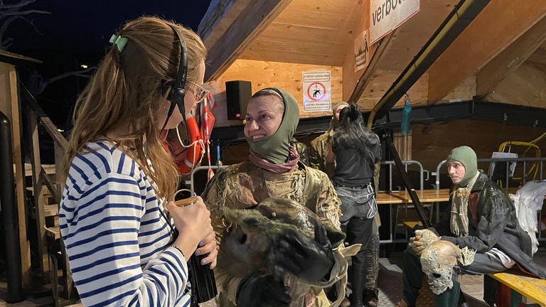 Solisten, Chor, Stuntleute, Maskenbildnerinnen und Regieassistentinnen wirbeln unter der Seebühne bei "Der Freischütz" der Bregenzer Festspiele.