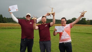 Die drei Sieger der Modellflug-WM in Heudorf: Emanuel Dähn in der Mitte als Weltmeister, links Philip Kolb auf Platz 2, rechts Hansgeorg Siegenthaler auf Platz 3.