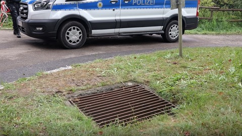 Abflussschacht an einer Straße, zum Teil  mit Gras überwuchert. Dass er übergelaufen ist, hat mutmaßlich den Personenzug wegen eines Hangrutsches bei Riedlingen zum Entgleisen gebracht. 