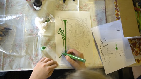 Ein Kind malt große Buchstaben nach: Im Museum auf der Reichenau dürfen Kinder schreiben wie die Mönche im Mittelalter.