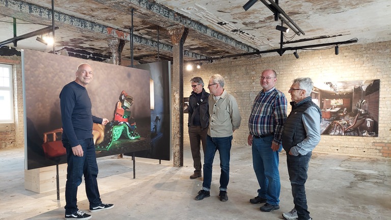 Mehrere Männer stehen im 2024 ausgebrannten Stadlerhaus in Konstanz. Dort ist jetzt eine Doppelausstellung zu sehen.