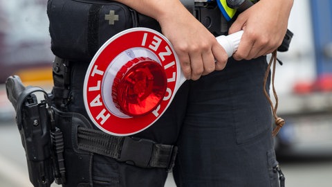 Eine Polizistin steht mit einer Polizeikelle an einer Autobahn.