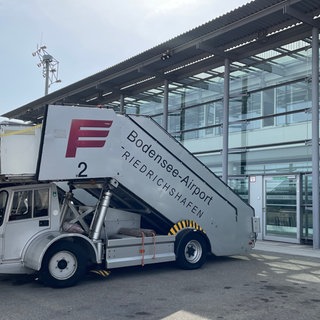 Ein Fahrzeug mit einer Fluggasttreppe am Flughafen Friedrichshafen. Wie wirkt sich die Absenkung der Luftverkehrssteuer auf die Preise für Flugtickets aus?