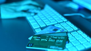Auf einer Computertastatur liegen Kreditkarten. Ein Rentner aus dem Kreis Ravensburg hat über eine Million Euro an Anlagebetrüger verloren.