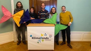 Verantwortliche der Stadt und Vertreter von Projekten, die durch den Konstanzer Klimafonds gefördert wurden, stehen mit großen Papierschmetterlingen vor einem Banner
