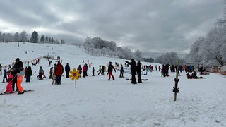 Dunkle Wolken über Wintersportlern am Felderhaldelift in Isny. Aber es liegt Schnee.