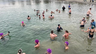 Mitglieder der DLRG-Ortsgruppe Salem baden beim Anbaden im Januar 2025 gemeinsam im kalten Schlosssee in Salem am Bodensee.