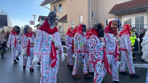 Maskenträger im weißen Häs ziehen durch Neuravensburg.