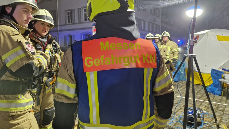 Nahaufnahme des Rückens eines Feuerwehrmannes beim Großeinsatz in Konstanz, auf der Einsatzkleidung steht "Messen Gefahrgut KN".