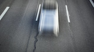 Ein Auto rauscht schnell auf einer Autobahn vorbei.