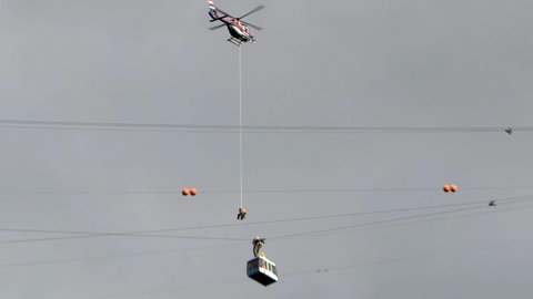 Ein Retter seilt sich aus einem Hubschrauber ab zur Karrenseilbahn.