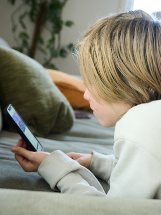 Ein Junge schaut in ein Smartphone (Symbolbild): Immer mehr Kinder haben bereits in der Grundschule ein Handy.
