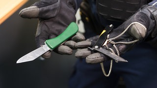 Ein Polizist präsentiert Messer, die bei Kontrollen sichergestellt worden sind (Symbolbild): Die Polizei will während der Fastnacht verstärkt Kontrollen auf Messer und andere gefährliche Gegenstände durchführen.