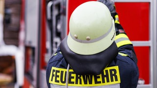 Ein Feuerwehrmann steht vor einem Einsatzfahrzeug (Symbolbild): Die Feuerwehr Bad Saulgau rückte am Donnerstag zu einem Einsatz in einem Kindergarten aus. Dort war eine Heizung aus der Wand gefallen.