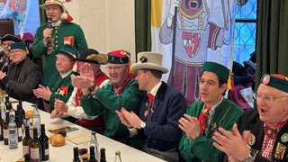 Ministerpräsident Winfried Kretschmann (Grüne) und CDU-Spitzenkandidat Manuel Hagel sitzen im Ratssaal in Riedlingen beim Froschkuttelnessen nebeneinander.