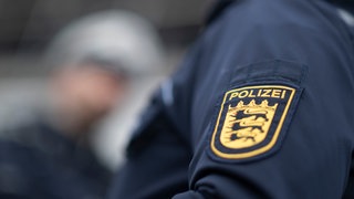Ein Polizist und eine Polizistin der Polizei Baden-Württemberg stehen in einem Industriegebiet. In Uhldingen-Mühlhofen im Bodenseekreis waren laut Polizei Anfang der Woche drei Betrüger unterwegs. (Symbolbild)