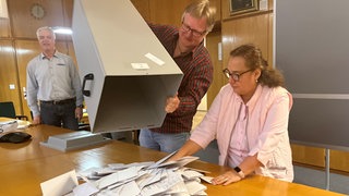 Wahlhelferinnen und Wahlhelfer zählen in einem Wahllokal in Friedrichshafen (Bodenseekreis) Stimmzettel aus.