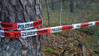 Ein Absperrband der Polizei an einem Baum. Bei Riedlingen hat ein Spaziergänger Knochen eines Vermissten gefunden.