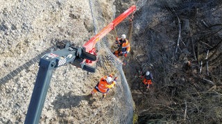 Arbeiter einer Spezialfirma bauen ein Stahlnetz über eine 45 Meter hohe Felswand in Biberach.
