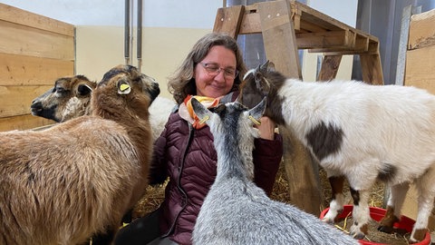 Andrea Göhring sitzt im Schafstall und streichelt ihrer Tiere. Sie bietet auf ihrem Hof tiergestützte Therapie mit Bauernhoftieren an. 