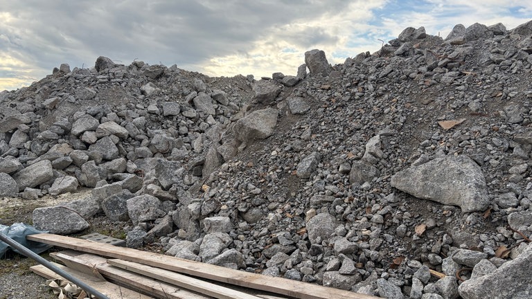 Blick durch einen Bauzaun auf eine Baustellenfläche mit gelagertem Material bei Allensbach. 