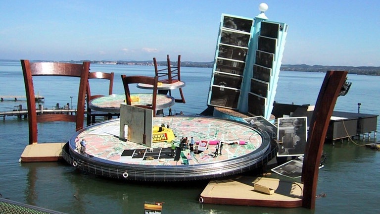 Ein Riesentisch und zwei Stühle als Bühnenbild der Bregenzer Festspiele auf der Seebühne im Bodensee
