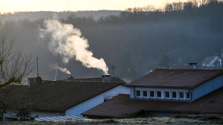 Rauchender Kamin im Morgenlicht. Die Hochschule Biberach forscht zu "Transformation von Einfamilienhausgebieten". (Symbolbild)