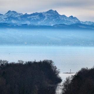 Der Berg Säntis mit seinem Masten auf dem Gipfel ragt hinter dem Bodensee über dem Dunst heraus.