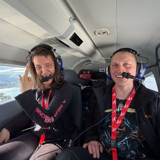 Marleen und ihr Verlobter Matthias sitzen im Flugzeug. Durch die Fenster ist der Bodensee zu sehen.