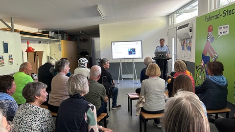 Rund 20 Teilnehmer sitzen in einem Raum auf dem Verkehrsübungsplatz in Friedrichshafen. Beim Fahrsicherheitstraining in Friedrichshafen wurde ihnen alles rund ums Pedelec gezeigt.