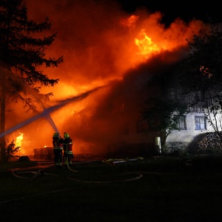 Flammen schlagen aus einem Bauernhof in Amtzell. Feuerwehrleute versuchen den Brand zu löschen.