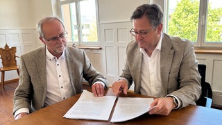 Historiker Clemens Rehm (links) und Owingens Bürgermeister Henrik Wengert lesen im historischen Aufsatz zur Aufarbeitung nationalsozialistischen Verbrechen.