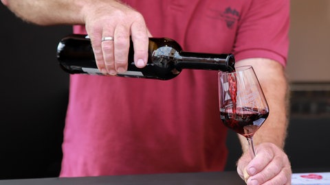 Eine Person schenkt ein Glas Rotwein ein