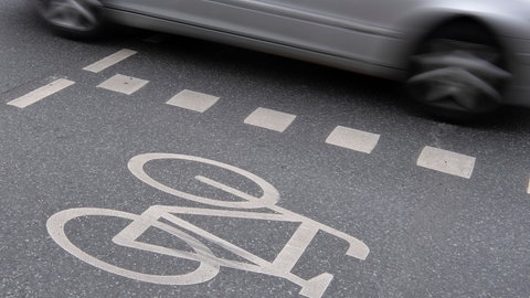 Ein Auto fährt neben einem Radweg (Symbolbild)