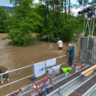 Die Bühne der Gruppe Theater im Fluss steht im Wasser. Helfer waten durchs Wasser.