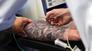 Ein Mann mit einem tätowierten Arm beim Blutspenden