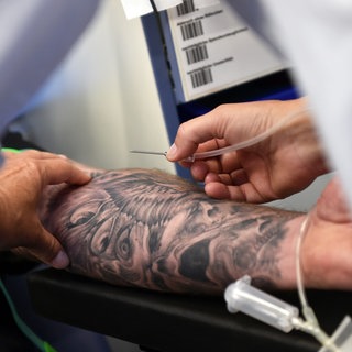 Ein Mann mit einem tätowierten Arm beim Blutspenden