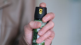 Eine Hand auf diesem Symbolbild hält eine Kartusche mit Pfefferspray.