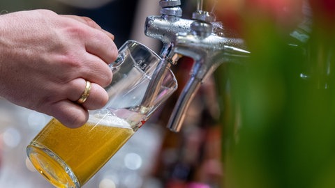 Ein Mann gießt Bier vom Zapfhahn ins Glas. 