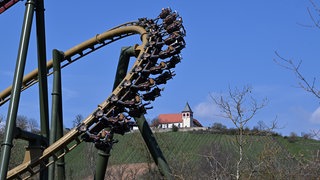 Auf einer Achterbahn im Freizeitpark Tripsdrill bei Cleebronn fahren Besucher vor dem Michaelsberg mit der Michaelskirche. Im April kam es zu einem Unfall mit einem Storch.