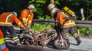 Die Feuerwehr Schwäbisch Hall löscht nach einem Unfall ein brennendes Motorrad auf der Straße