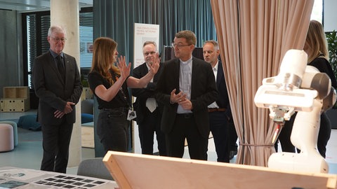 Kirche trifft KI: Franziska Kirchert erklärt Bischof Klaus Krämer in den IPAISpaces, wie mit Hilfe Künstlicher Intelligenz ein Kunstwerk entstanden ist.  