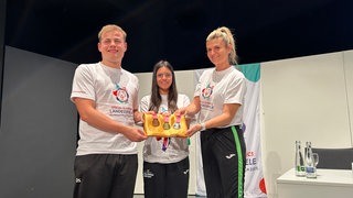 Die Special Olympics in Heilbronn und Neckarsulm sind gestartet. Die drei Botschafter der Spiele zeigen die Medaillen in die Kamera.