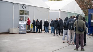 Noch vor einem halben Jahr Bilder wie dieses: Geflüchtete Menschen stehen Schlange vor einer Unterkunft. Die Zahl der Zuweisungen hat in Baden-Württemberg abgenommen, die Landkreise in der Region Heilbronn-Franken reagieren. (Symbolbild)