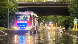 Ein Feuerwehrauto an einer überfluteten Straße in Heilbronn. Auch in Hohenlohe kam es zu Überschwemmungen, in Neckarsulm gab es einen Blitzeinschlag.