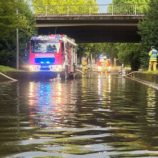 Ein Feuerwehrauto an einer überfluteten Straße in Heilbronn. Auch in Hohenlohe kam es zu Überschwemmungen, in Neckarsulm gab es einen Blitzeinschlag.