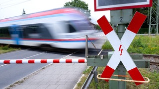 Ein Zug fährt an einer geschlossenen Bahnschranke vorbei (Symbolbild): In Bad Friedrichshall kam es zu einem Zugunfall, weil ein Fahrrad auf den Gleisen lag. Dieser gefährliche Eingriff in den Bahnverkehr ist kein Einzelfall.