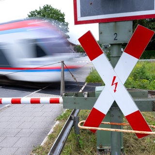 Ein Zug fährt an einer geschlossenen Bahnschranke vorbei (Symbolbild): In Bad Friedrichshall kam es zu einem Zugunfall, weil ein Fahrrad auf den Gleisen lag. Dieser gefährliche Eingriff in den Bahnverkehr ist kein Einzelfall.