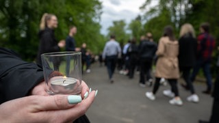 Gäste einer Trauerfeier halten Kerzen (Symbolbild)