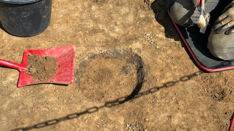 In der Erde stecken die Reste eines alten Krugs, der vorsichtig ausgegraben wird. Er wurde bei Grabungen für die Stromtrasse "SuedLink" entdeckt.